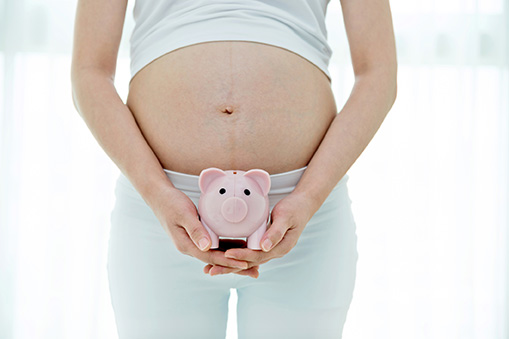 woman pregnant holding a piggy bank